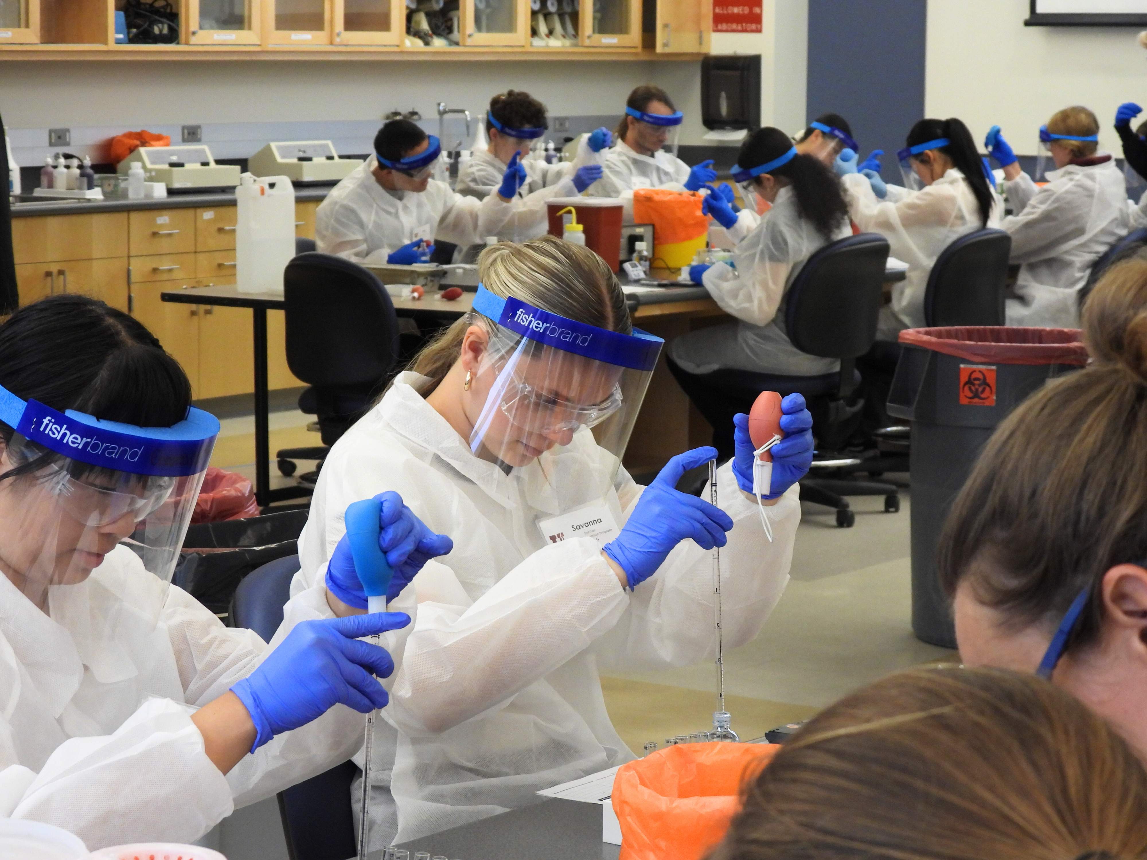 Summer immersion student performs an experiment while wearing PPE.